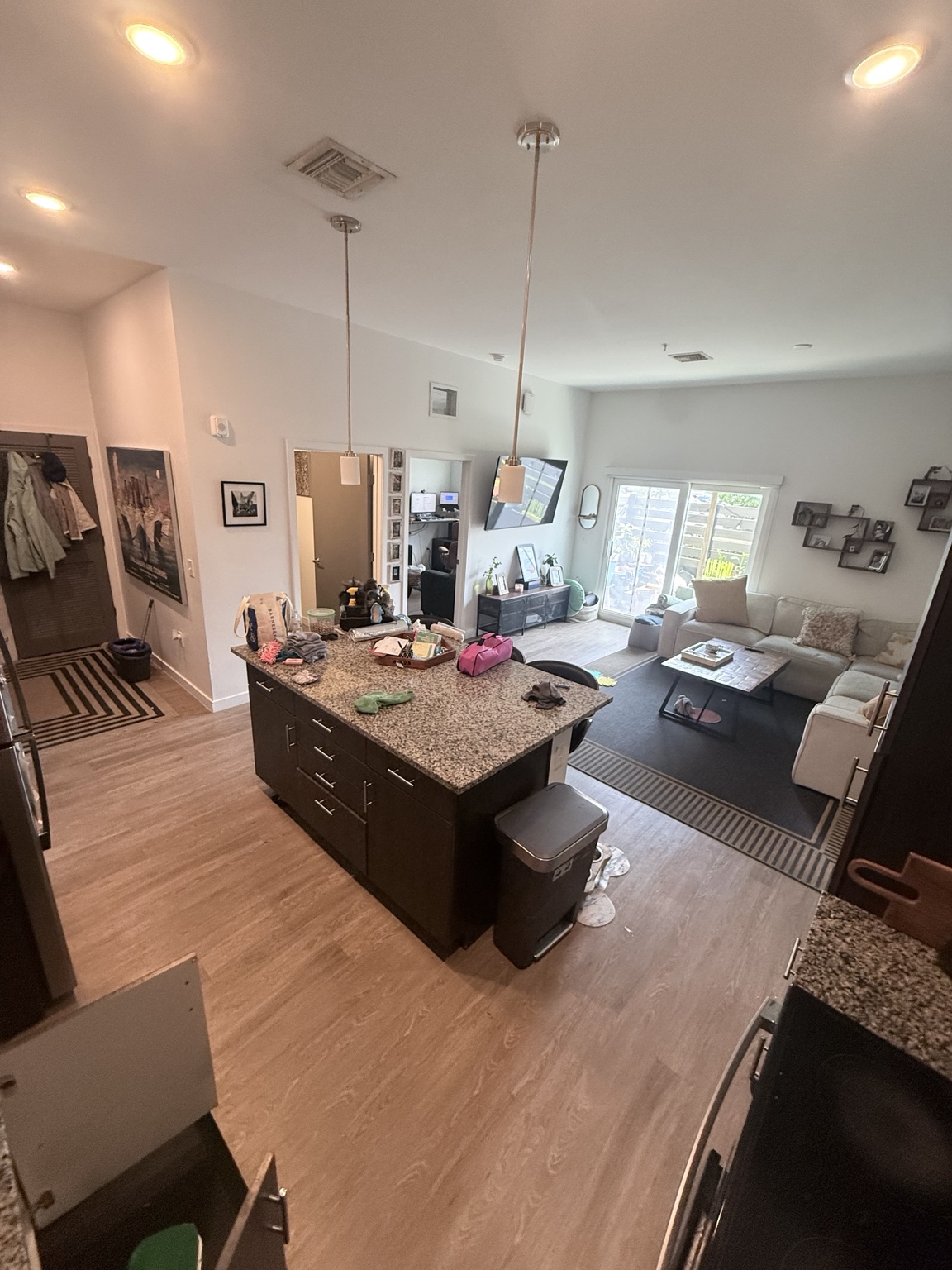 Kitchen and living area before cleaning, with items on the counters and floor