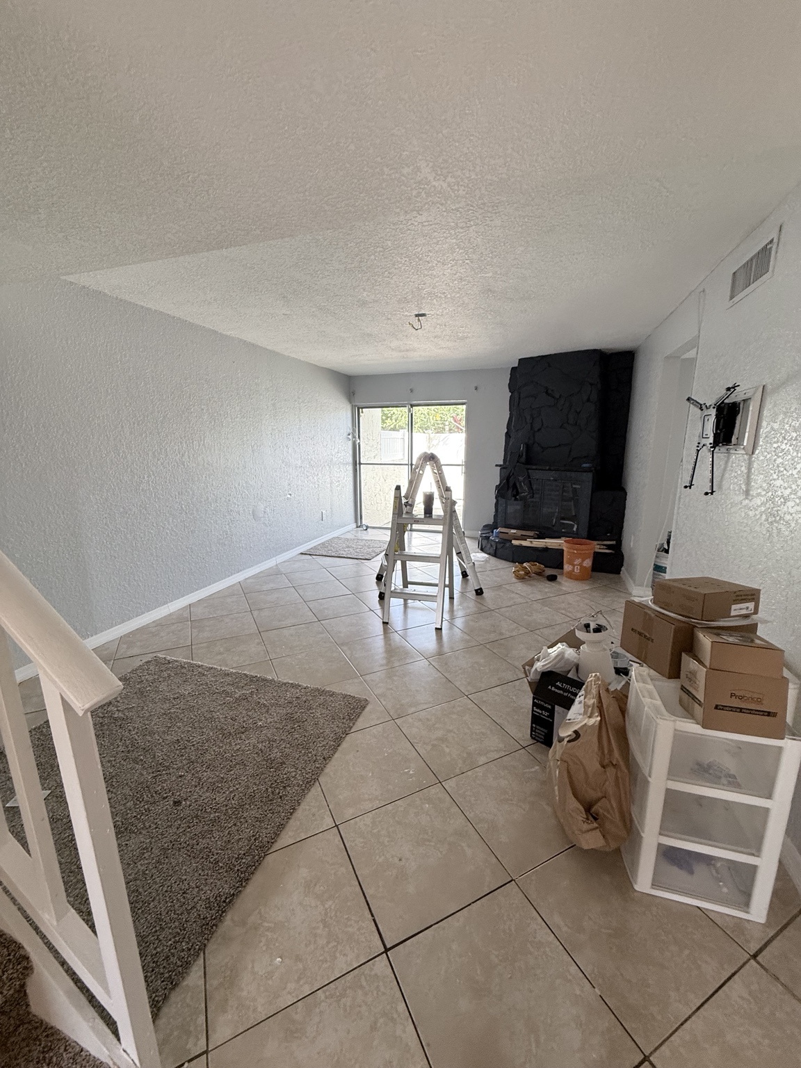 Living area before post-construction cleaning, with a ladder, boxes, and project materials