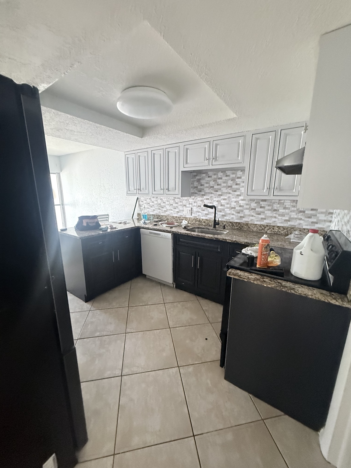 Kitchen before post-construction cleaning, with cleaning supplies and items on the counters